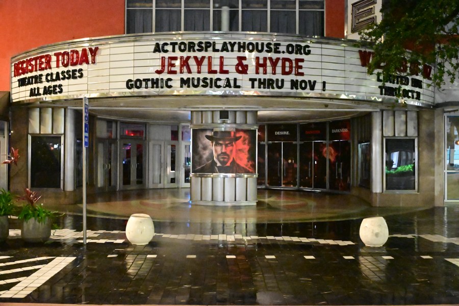 The theater entrance reflected in the wet pavement