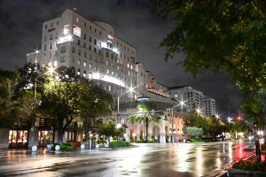 An illuminated corner building beyond a rain-soaked road
