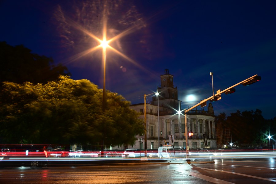 Light trails beneath the clock tower and a starburst streetlight